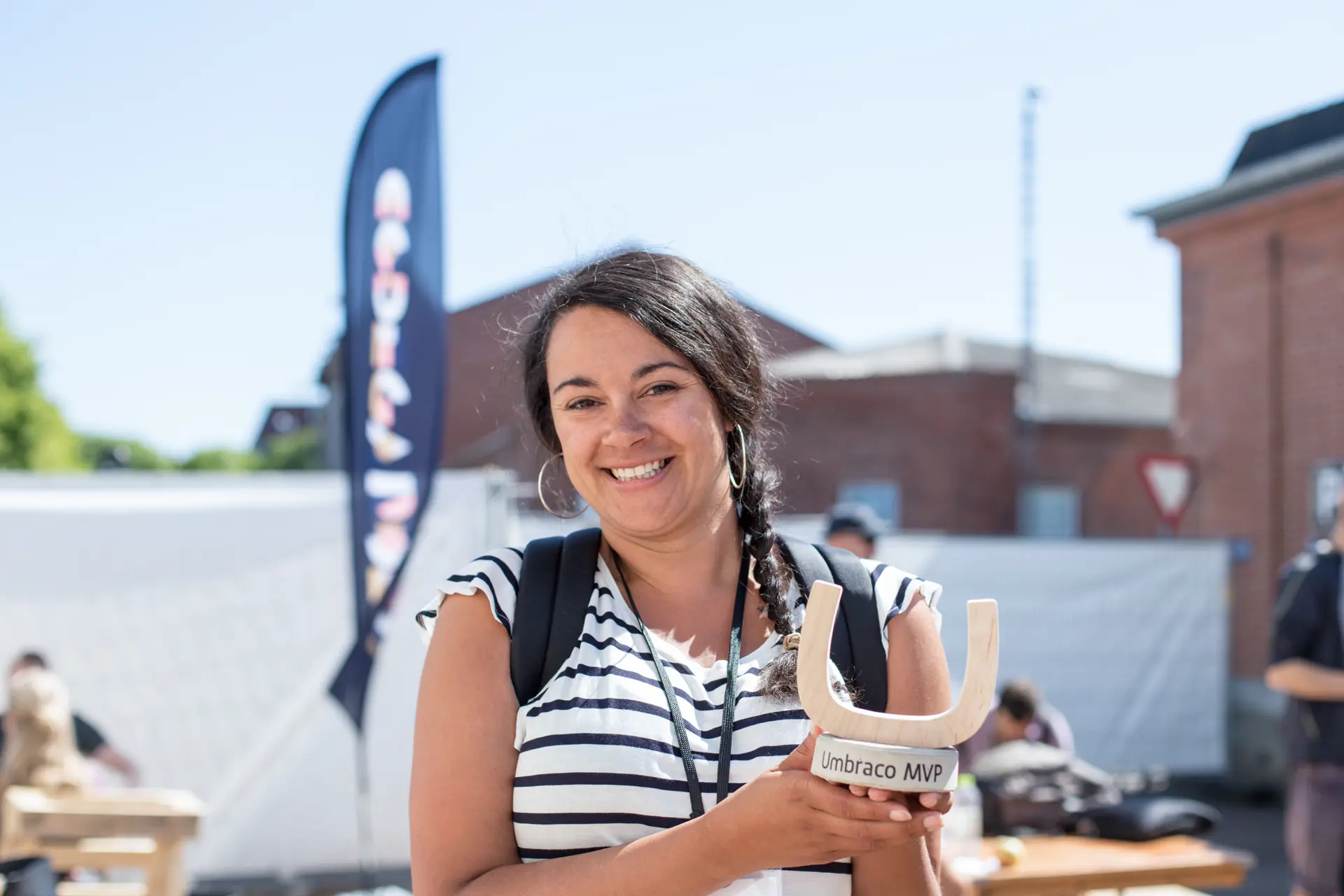 MVP Emma Burstow wearing a striped white and blue top holding up an MVP award in both hands, smiling with excitement.