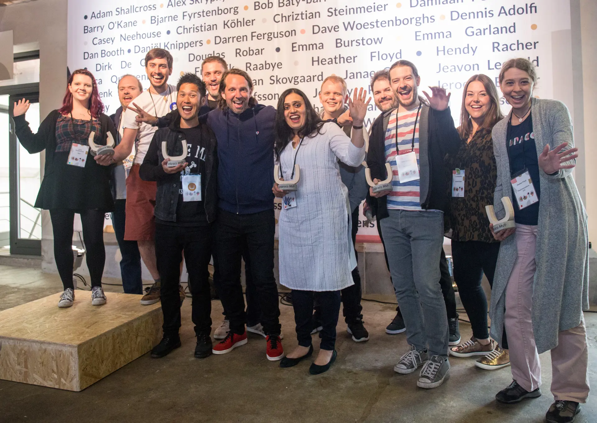 Umbraco Founder Niels Hartvig stands together with 11 happy new MVPs at Codegarden 2019. Behind them is a wall with all MVPs names. 